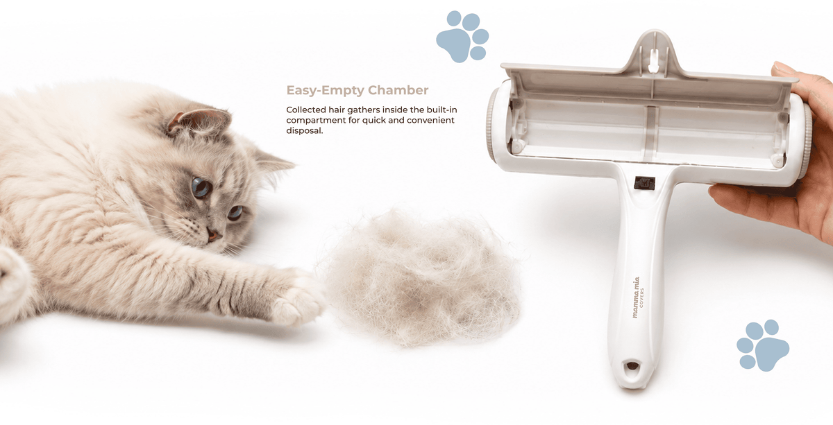 A white pet hair remover with a transparent collection chamber is shown on a white background, held by a hand. A fluffy cream-colored cat lies on the left, with a pile of collected fur in the center.